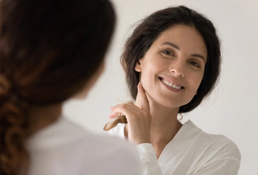 older woman smiling at herself in the mirror looking good | Ingram Cosmetic Surgery Nashville