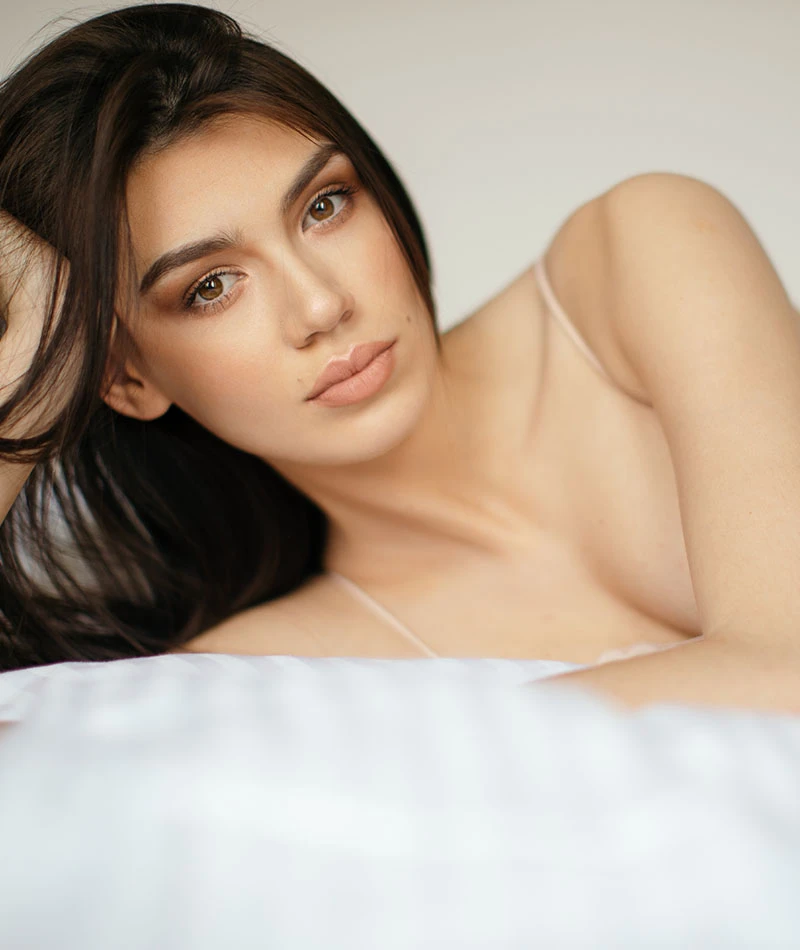 beautiful woman leaning against arm in bed | Ingram Cosmetic Surgery