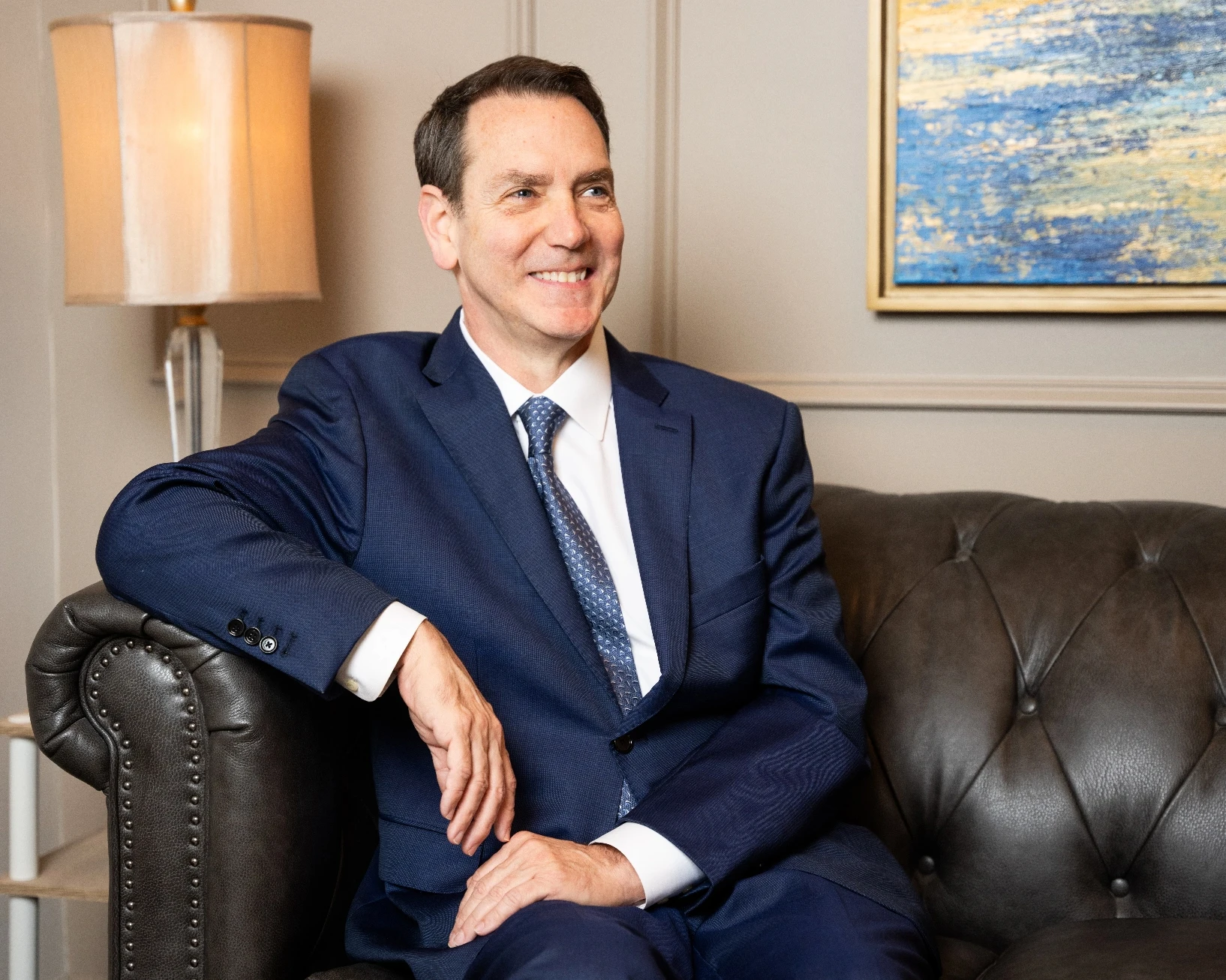 dr ingram smiling and sitting on a leather couch | Ingram Cosmetic Surgery Nashville